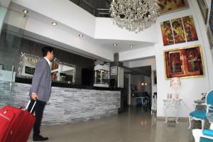 a man walking through a lobby with a red suitcase at Hotel Vila Santa in Lima