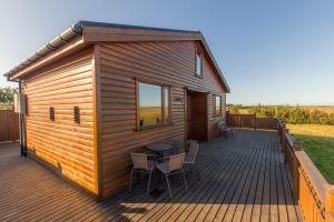 Cabaña de madera con mesa y sillas en una terraza en Cozy Cottage by Stay Iceland, en Hvolsvöllur