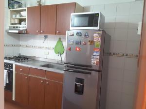 a kitchen with a refrigerator with a microwave on top of it at Apartment Riberas in Cali