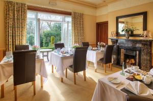 una sala da pranzo con tavoli, sedie e camino di Fairfield House a Warkworth