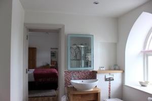 a bathroom with a white sink and a bedroom at Tudor Lodge Bed & Breakfast in Manorbier