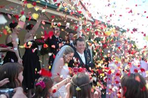 a bride and groom walking through a crowd of confetti at Reid's Place in Redcliffe