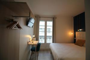 a bedroom with a bed and a desk and a window at Hôtel La Fontaine Caen Centre in Caen