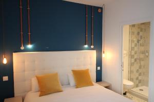 a bedroom with a white bed with a blue wall at Hôtel La Fontaine Caen Centre in Caen
