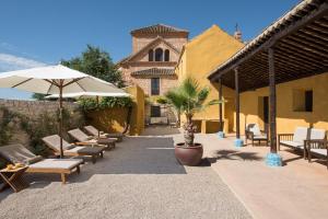 eine Terrasse mit Stühlen, einem Sonnenschirm und einem Gebäude in der Unterkunft Hotel Cortijo del Marqués in Albolote