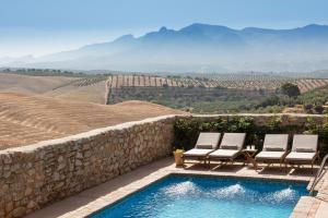 a swimming pool with two chairs and a stone wall at Hotel Cortijo del Marqués in Albolote
