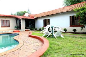 a patio with two chairs and a table next to a house at Harmony Guest House in Johannesburg