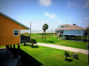 a house with a grassy yard next to the ocean at 1 Coastal Calm Home in Bolivar Peninsula