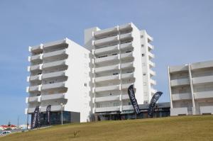 two tall white buildings with signs in front of a field at Baleal Tower Bay Apartment in Ferrel