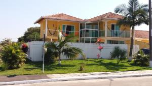 a yellow house with palm trees in front of it at Praia com Conforto in Guaratuba