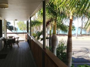 un porche con palmeras y una mesa. en Coconut Palms On The Bay en Hervey Bay