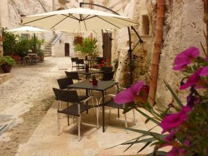 een groep tafels en stoelen met een paraplu bij Hotel San Giorgio in Matera