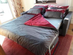 uma cama com almofadas vermelhas e cinzentas em Walnut Tree House em Neulengbach