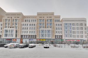 un gran edificio con coches estacionados en un estacionamiento en Apartments LUX 53/144, en Astana