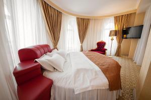 Habitación de hotel con cama roja y silla en Salut New Moscow Hotel, en Vnukovo