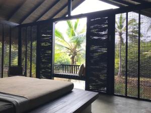 a bedroom with a bed and a large window at KAJU GREEN eco lodges in Unawatuna