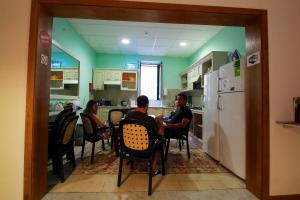 a group of people sitting at a table in a kitchen at Corner Hostel in Sliema