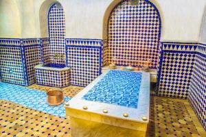 baño con azulejos azules y blancos y bañera en Riad Alya en Fez