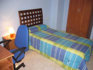 um quarto com uma cama azul e uma cadeira azul em Piso en calle Campo em Tomelloso