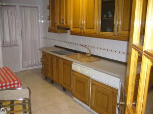 uma cozinha com armários de madeira e um lavatório em Piso en calle Campo em Tomelloso