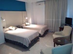 Habitación de hotel con 2 camas, escritorio y silla en Hotel Nuevo Ara, en Cáceres