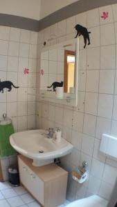 een badkamer met een wastafel en een zwarte kat aan de muur bij Ferienwohnung Katzenberger in Beverungen