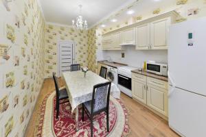 kuchnia ze stołem i lodówką w obiekcie Apartments LUX 53/144 w mieście Astana