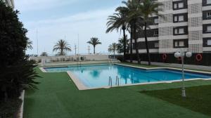 a swimming pool in front of a building at Apartamento en 1ª LINEA Playa de Gandia in Gandía