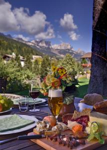 a table with a glass of wine and food on it at Hotel Catinaccio Rosengarten in Moena