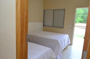 a bedroom with two beds and a window at Condomínio Recanto dos Dourados - Casa de Temporada in Três Marias +11 photos