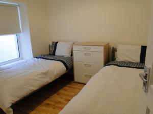 a bedroom with two beds and a dresser and a window at Tri ard house Derry city centre STILL OPEN in Derry Londonderry