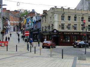 a city street with people walking and cars on the road at Tri Ard House Derry City Centre town house in Derry Londonderry