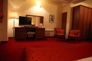 um quarto de hotel com televisão e duas cadeiras em Hotel Belvedere em Ohrid