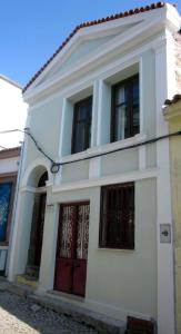 ein weißes Haus mit roten Türen auf einer Straße in der Unterkunft Paydos Tatil Evi in Ayvalık