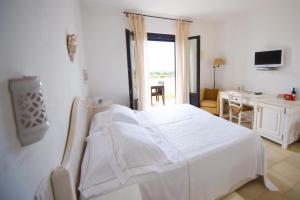 a white bed in a white room with a desk and a computer at Borgobianco Resort & Spa Polignano - MGallery Collection in Polignano a Mare