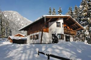 una cabaña de madera en la nieve con árboles nevados en Ferienwohnung Achten, en Waidring