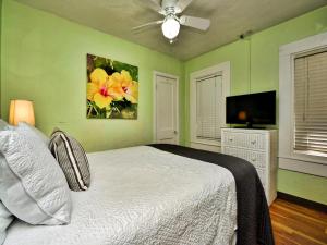 een groene slaapkamer met een bed en een plafondventilator bij Palm Place 2 - Coconut Palm Beach getaway 623 in Clearwater Beach