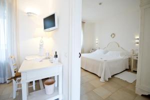 a bedroom with a bed and a table and a tv at Borgobianco Resort & Spa Polignano - MGallery Collection in Polignano a Mare