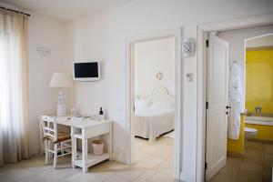 a white room with a bed and a desk and a table at Borgobianco Resort & Spa Polignano - MGallery Collection in Polignano a Mare
