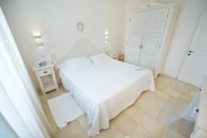 a white bedroom with a white bed and a white cabinet at Borgobianco Resort & Spa Polignano - MGallery Collection in Polignano a Mare