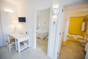 a white bathroom with a desk and a bed at Borgobianco Resort & Spa Polignano - MGallery Collection in Polignano a Mare