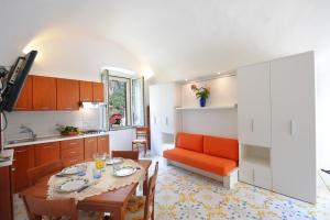 a kitchen and dining room with a table and orange couch at Relais San Basilio Convento in Amalfi