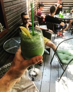 uma mão segurando uma bebida verde com uma banana em Club Robert Motel em Hîrşova