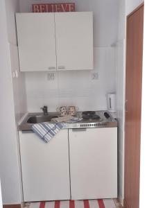 a small kitchen with white cabinets and a sink at Mini Apartament MARINE in Świnoujście