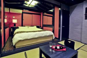 een slaapkamer met een bed en 2 tafels met wijnglazen bij Hotel Sakura-saku (Adult Only) in Fukuoka