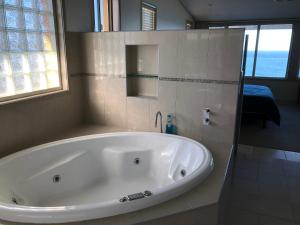 a white bath tub in a bathroom with a window at OceanScape Luxury Beachfront Villas in Scotts Head