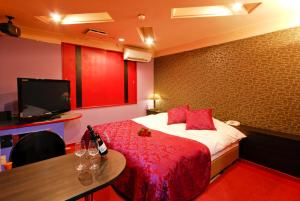 Habitación de hotel con cama, mesa y TV en Hotel Joy (Love Hotel) en Onga