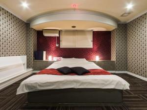 een slaapkamer met een groot bed met 2 kussens erop bij Hotel TiAMO (Love Hotel) in Kitakyushu