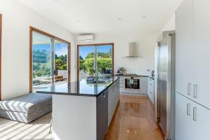 a kitchen with white walls and a large window at Karaka Sanctuary with Spa Pool by Waiheke Unlimited in Oneroa