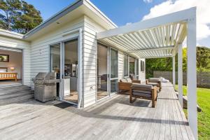 an outdoor deck with a pergola and a grill at Karaka Sanctuary with Spa Pool by Waiheke Unlimited in Oneroa